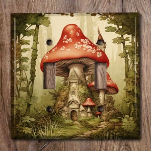 May include: A whimsical light switch cover featuring a fantasy mushroom house scene. The design includes a large red mushroom with white spots, a small tower, and a forest backdrop. The cover has two switch openings and is square-shaped.