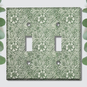 May include: A green and white floral patterned light switch cover with two toggle switches.