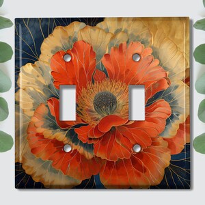 May include: A light switch cover featuring a close-up of a large, red and gold flower with intricate details. The flower has a dark blue background with gold accents.
