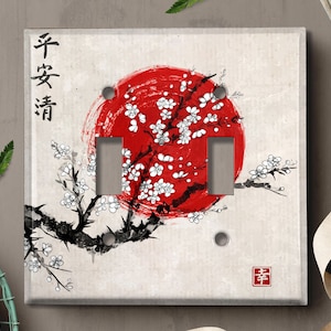May include: A light switch cover with a red and white Japanese-inspired design. The design features a red circle with white cherry blossoms and a black branch with thorns. The text "平安清" is written in black on the left side of the cover. The text "幸" is written in red on the right side of the cover.