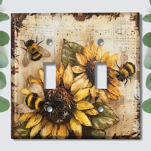May include: A light switch cover with a vintage design featuring sunflowers, bees, and musical notes. The cover has a distressed, rustic look and is perfect for adding a touch of farmhouse charm to any room.