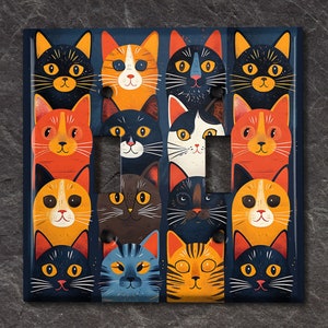 May include: A light switch cover with a colorful design featuring a repeating pattern of cats with different colored fur and facial expressions. The cats are arranged in rows and columns, creating a playful and whimsical design.