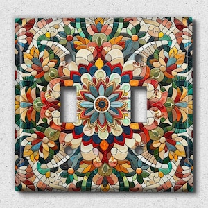 May include: A decorative light switch cover with a colorful mosaic pattern featuring floral designs and geometric shapes. The cover has two toggle switches.