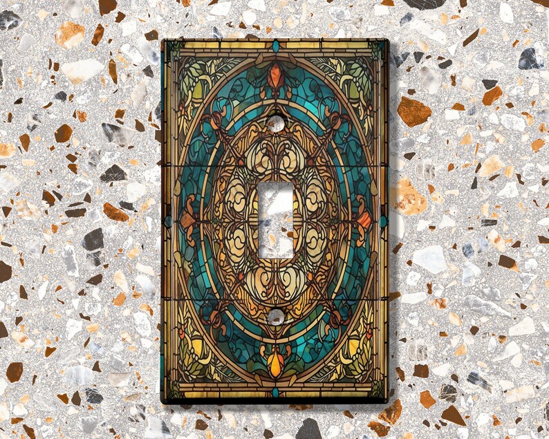 May include: A light switch cover with a stained glass design featuring a circular pattern in shades of blue, gold, and brown.