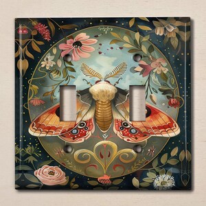 May include: A light switch cover with a whimsical design featuring a large, colorful moth with intricate details. The moth is surrounded by flowers and foliage, creating a vibrant and enchanting scene.