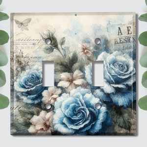 May include: A light switch cover with a vintage floral design featuring blue roses, white flowers, and green leaves on a cream background. The text "A E RESTN" is visible in the upper right corner.