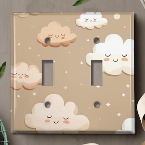 May include: A light brown light switch cover with a pattern of white and beige clouds with smiling faces. The clouds have a cartoon-like appearance.