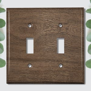 May include: A brown woodgrain light switch cover with two toggle switches and two screw holes.