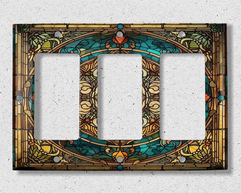 May include: A triple light switch cover with a stained glass design featuring a blue, green, and gold color scheme. The design is intricate and features floral and geometric patterns.