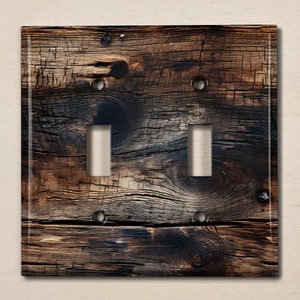 May include: A rustic wooden light switch cover with a distressed, weathered look. The cover has two toggle switches and is made from reclaimed wood.
