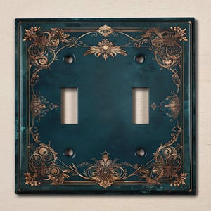 May include: A teal blue light switch cover with a gold ornate design. The switch cover has two toggle switches.
