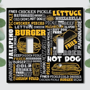 May include: Black light switch cover with a white background and yellow text. The text includes a list of food items, including "burger", "fries", "hot dog", "lettuce", "pickles", "onion", "jalapeno", "mayo", "mozzarella", "cold drinks", "chicken", "beef", and "mushroom".