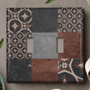 May include: A decorative light switch cover with a geometric pattern in shades of brown, black, and white. The cover is made of a textured material that resembles tile.