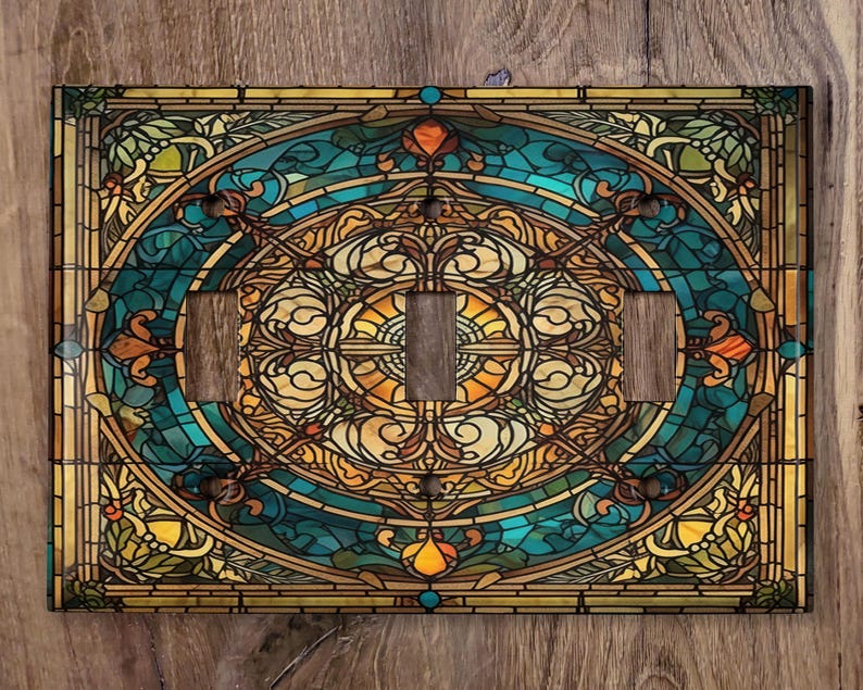 May include: A stained glass light switch cover with a circular design featuring blue, green, yellow, and brown colors. The design is intricate and features a variety of geometric shapes.