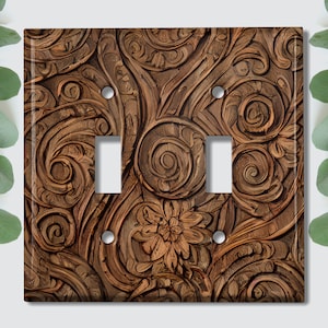May include: A brown wooden light switch cover with a carved floral design.