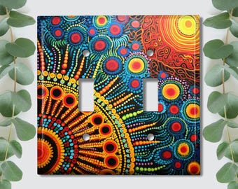 Könnte beinhalten: Ein farbenfroher Lichtschalter-Abdeckung mit einem geometrischen Muster aus Kreisen und Punkten in Rot-, Orange-, Gelb-, Blau-, Grün- und Schwarztönen. Das Design ähnelt der Aborigine-Kunst.