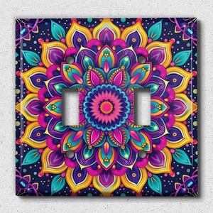 May include: A colorful mandala design with pink, yellow, blue, and purple hues on a dark blue background. The design is centered on a light pink flower with a yellow center. The design is printed on a light switch cover.