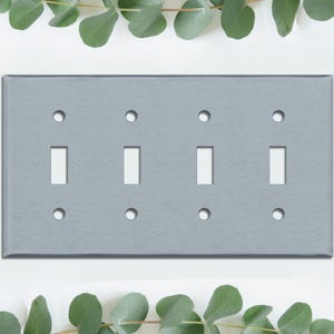 May include: A brushed nickel four-gang toggle switch plate with four toggle switch cutouts and six screw holes.
