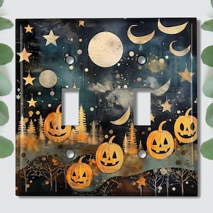 May include: A light switch cover with a Halloween theme. The design features a dark blue night sky with a full moon, stars, and crescent moons. There are five jack-o'-lantern pumpkins in the foreground, with a forest of trees behind them.
