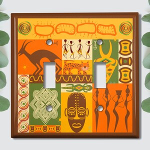 May include: A light switch cover featuring a colourful African-inspired design. The design incorporates geometric patterns, animals, and masks in shades of orange, yellow, green, and brown.