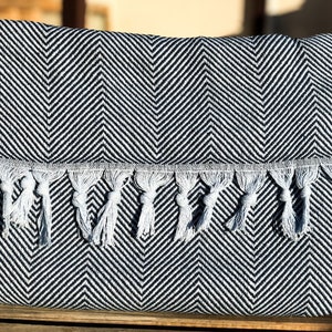 May include: Black and white chevron patterned throw blanket with white fringe tassels.