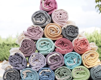 May include: A stack of colorful rolled towels, arranged in a triangular shape. The towels are made of a soft, absorbent material and feature a variety of patterns and colors, including pink, blue, green, yellow, and black.
