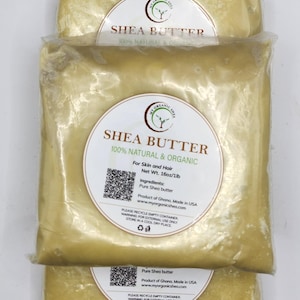 Könnte beinhalten: Drei versiegelte Beutel Sheabutter, gestapelt. Jeder Beutel hat ein weißes Etikett mit dem Text "SHEA BUTTER 100% NATURAL & ORGANIC" und Produktinformationen. Die Sheabutter ist hellgelb.