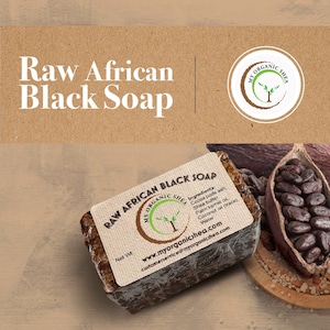May include: A bar of Raw African Black Soap with a brown paper label. The label has the text "Raw African Black Soap" and "My Organic Shea" with a logo of a tree. The ingredients are listed on the label: Cocoa pods ash, Shea butter, Palm kernel oil, Coconut oil (trace), Water. The soap is sitting on a wooden surface with cocoa pods and cocoa beans.