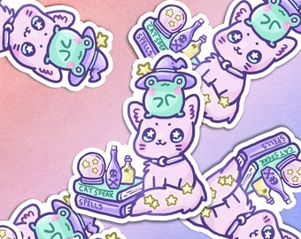 May include: A collection of stickers featuring a cute, light purple cat wearing a collar and a witch hat, with a green frog on its head. The cat is surrounded by stars, books with the text "CAT SPEAK SPELLS", potion bottles, and a crystal ball.