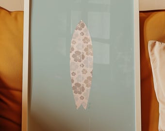 Könnte beinhalten: Ein gerahmter Kunstdruck mit einem Surfbrett-Design. Das Surfbrett ist hellrosa mit einem Blumenmuster in Braun- und Weißtönen. Der Hintergrund ist hellblau-grün und der Rahmen ist weiß. Das Kunstwerk wird auf einem senffarbenen Sofa präsentiert.