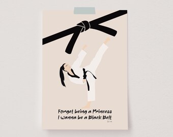 Op de afbeelding: Een vrouw in een wit karatepak voert een hoge trap uit met een zwarte band om haar middel. De tekst "Forget being a Princess I wanna be a Black Belt" is onder de afbeelding gedrukt.