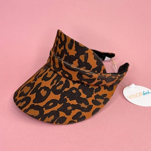 May include: A brown and black leopard print visor with a black headband and the text "VISOR Girl" on a white tag.