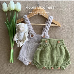 Può includere: Un set di tutina e bloomers per neonati lavorati a maglia in beige e verde, esposto su una gruccia di legno. La tutina presenta spalline intrecciate e bottoni di legno. Il testo "Robin Bloomers" e "Baby Knitting Pattern" sono visibili.