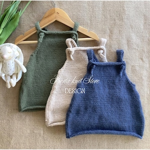 Puede incluir: Tres peleles de punto sin mangas en verde oliva, beige y azul marino, cada uno con tirantes anchos con detalles anudados. El texto Berta knit Store DESIGN está centrado sobre las prendas, que se muestran colgadas en una percha de madera.