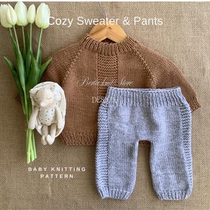 Può includere: Un maglione e pantaloni per neonati lavorati a maglia marroni e grigi sono esposti. Le parole "Cozy Sweater & Pants" sono in alto. Un coniglietto di peluche e tulipani sono a sinistra. Il testo "Baby Knitting Pattern" è in basso.