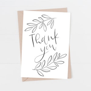 May include: A white card with a black handwritten thank you message and black floral illustrations.