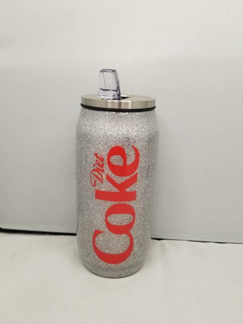 May include: Silver glitter tumbler with a red "Diet Coke" logo and a clear lid with a straw.