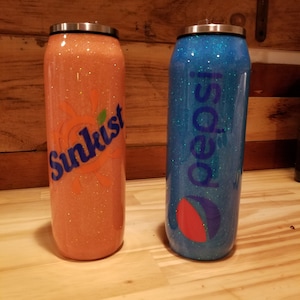 May include: Two glitter-covered stainless steel tumblers with lids. The tumbler on the left is orange with a Sunkist logo. The tumbler on the right is blue with a Pepsi logo.
