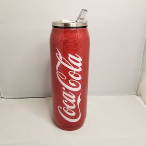 May include: Red glitter tumbler with a white Coca-Cola logo and a clear lid with a straw.