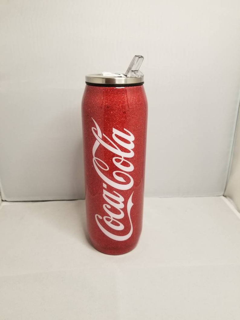 May include: Red glitter tumbler with a white Coca-Cola logo and a clear lid with a straw.