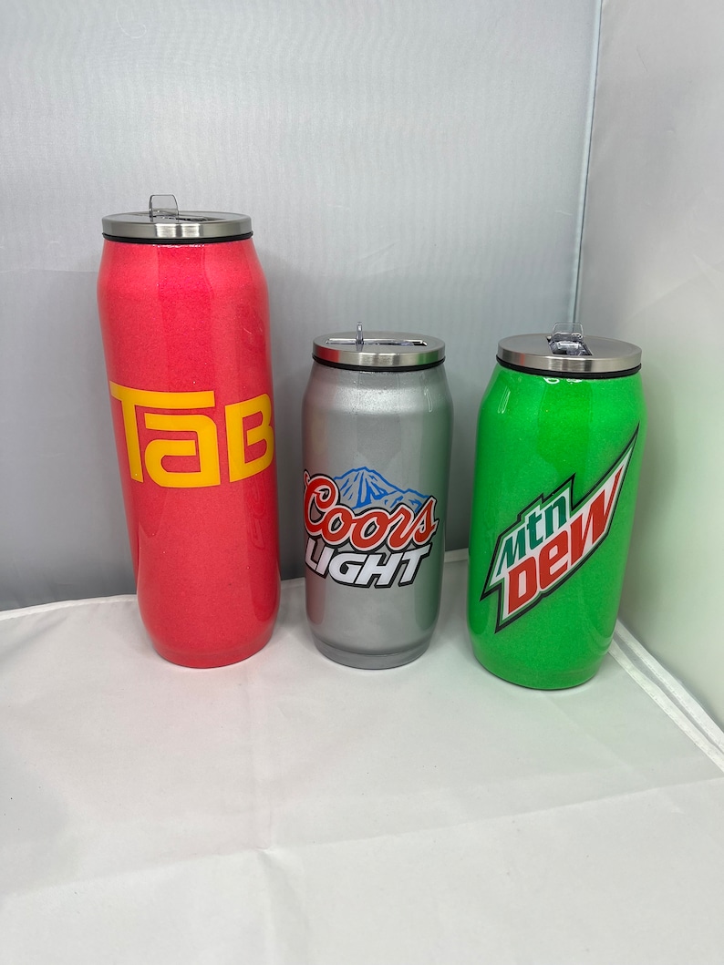 May include: Three stainless steel tumblers with lids. The tumblers are decorated with logos for Tab, Coors Light, and Mountain Dew.