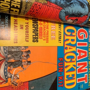 May include: A stack of vintage magazines with colorful covers. The top magazine features a blue elephant illustration. The second magazine has the text "NEWSPAPERS" and "FREE". The bottom magazine is titled "GIANT CRACKED FUN-KIT".
