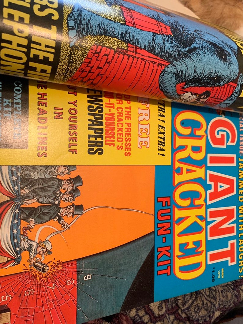 May include: A stack of vintage magazines with colorful covers. The top magazine features a blue elephant illustration. The second magazine has the text "NEWSPAPERS" and "FREE". The bottom magazine is titled "GIANT CRACKED FUN-KIT".
