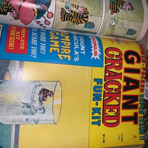 May include: A vintage comic book titled "Giant Cracked Fun-Kit" from October 1979. The cover is yellow with bold red and black text. The comic features cartoon illustrations and the text "Count Dracula's Vampire Game".