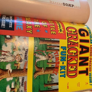 May include: A stack of vintage Cracked magazine issues. The top issue features a cartoon illustration with the words "GIANT CRACKED FUN-KIT" and "TIMBER!" in bold letters. The cover is yellow, red, and green. The magazine also advertises "Chicken Soap".