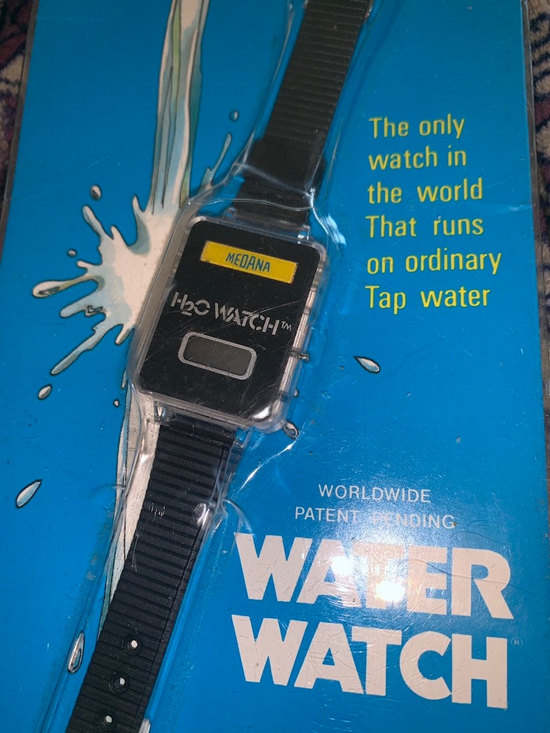 May include: A black and silver water-powered watch with the text "H₂O WATCH&trade;" and "MEDANA" on the face. The watch is packaged on a blue background with the text "The only watch in the world That runs on ordinary Tap water" and "WORLDWIDE PATENT PENDING WATER WATCH".