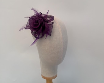 May include: A purple fabric rose with feathers, a popular choice for wedding hair accessories.