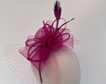 May include: A fuchsia pink hair comb with a large flower made of tulle and a single feather. The comb is decorated with a delicate net veil.