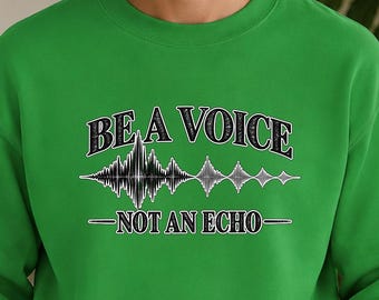 Op de afbeelding: Een felgroene sweater met ronde hals voorzien van de tekst BE A VOICE NOT AN ECHO in zwart-witte letters, vergezeld van een centrale zwart-witte afbeelding van een geluidsgolfpatroon op de borst van het kledingstuk.