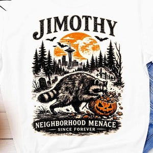 Könnte beinhalten: Ein weißes T-Shirt mit einer Grafik, die einen Waschbären mit einem Kürbiskopf, einen Wald, die Space Needle und einen Vollmond zeigt. Der Text lautet JIMOTHY NEIGHBORHOOD MENACE SINCE FOREVER. Das Design ist in schwarzer und oranger Farbe gedruckt.
